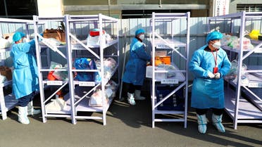 Workers wearing protective suits following the coronavirus disease (COVID-19) outbreak stand next to daily necessities placed on makeshift delivery racks, at a residential compound under lockdown after a case of the Omicron variant was detected, in Beijing's Haidian district, China January 18, 2022. (Reuters)