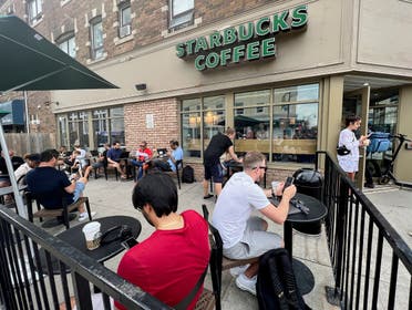 People crowd around a Starbucks coffee shop to use its free wifi on the Bell network, during a major outage of Rogers Communications’ mobile and internet networks which caused widespread disruptions across Canada, in Toronto, Ontario, Canada, on July 8, 2022. (Reuters)