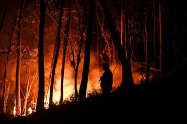 A silhouette of a firefighter standing in the forest is pictured during a wildfire at Casais do Vento in Alvaiazere on July 10, 2022. Around 1.500 firefighters were mobilized to put out three wildfires raging for more than 48 hours in central and northern Portugal, as the country was hit by a heat wave that prompted the government to declare a state of contingency.