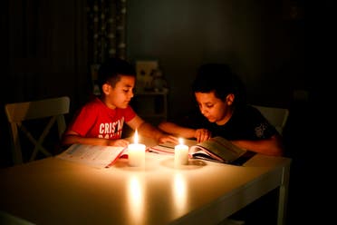 طفلان يدرسان على ضوء الشموع في طرابلس في يونيو الماضي