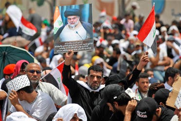 A supporter of Iraqi Shia cleric Muqtada al-Sadr lifts a placard depicting him during a collective Friday prayer in Sadr City, east of Baghdad on July 15, 2022. (AFP)