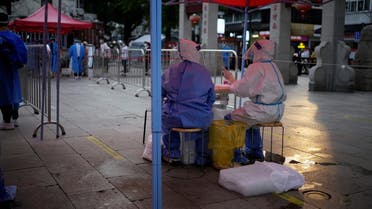 Medical workers in protective suits sit with ice blocks at a nucleic acid testing site amid a heatwave warning, following the coronavirus disease (COVID-19) outbreak in Shanghai, China, on July 12, 2022. (Reuters)