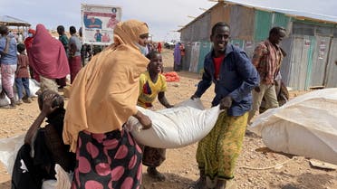 People carry bags of relief grains at a camp for the Internally Displaced People in Adadle district in the Somali region, Ethiopia, January 22, 2022. (Reuters)