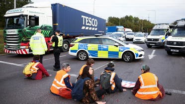 Insulate Britain activists with their hands glued to the ground block a roundabout at a junction on the M25 motorway during a protest in Thurrock, Britain October 13, 2021. (File photo: Reuters)