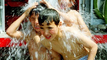 Lebanese children cool themselves with water from a fire engine in the port-city of Sidon on July 8, 2000. (File photo: Reuters)