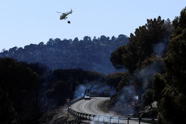A helicopter carries water to help extinguish a wildfire, as the country experiences a heatwave, at a lake in Cebreros, Avila, Spain, July 21, 2022. (Reuters)