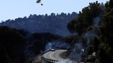 A helicopter carries water to help extinguish a wildfire, as the country experiences a heatwave, at a lake in Cebreros, Avila, Spain, July 21, 2022. (Reuters)