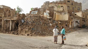 People chat as they stand in front of buildings damaged by war in Taiz, Yemen May 20, 2022. (Reuters)