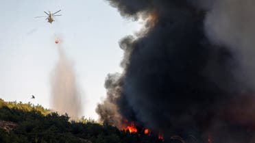 A firefighting helicopter makes a water drop as wildfire burns in the village of Vatera, on the island of Lesbos, Greece July 23, 2022. (Reuters)