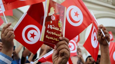 A demonstrator holds a copy of the Tunisian constitution, during a protest against Tunisian President Kais Saied in Tunis, Tunisia, Sunday, Sept. 26, 2021. More than 100 officials of Tunisia’s Islamist party Ennahdha have announced their resignations to protest their leadership's inability to confront the nation's political crisis. The split within the ranks of Ennahdha comes amid deep political crisis in Tunisia. President Kaïs Saied decided in July to sack the country’s prime minister, suspend parliament and assume executive authority, saying it was because of a national emergency. His critics called it a coup. (AP Photo/Hassene Dridi)
