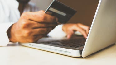 Stock photo of a man holding a credit card to make a purchase online. (Unsplash, Rupixen)
