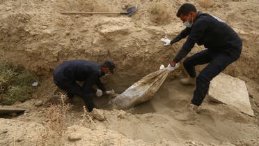 Workers hold an unidentified body at a mass grave in Raqqa, Syria October 16, 2018. Picture taken October 16, 2018. REUTERS/Aboud Hamam