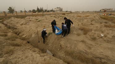 Workers hold an unidentified body at a mass grave in Raqqa, Syria October 16, 2018. (File photo: Reuters)