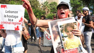 A demonstrator gestures as she holds a picture of Alexandra Najjar, a victim of August 2020 Beirut port blast, during a protest marking the two-year anniversary of the explosion, in Beirut Lebanon August 4, 2022. (Reuters)