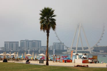 People gather at a beach across from the Ain Dubai Ferris wheel, on a foggy day on January 21, 2021, in the Gulf emirate of Dubai. (AFP)