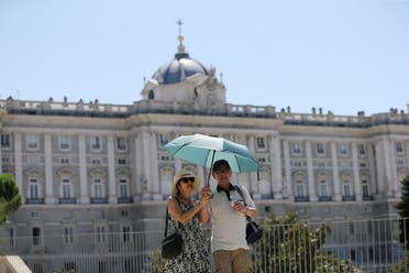 Tourists shelter from the sun under an umbrella near the Royal Palace during a hot day with temperatures reaching 37 Celsius degrees celsius (98.6 Fahrenheit degrees) in Madrid, Spain, August 9, 2022. (Reuters)