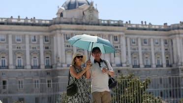 Tourists shelter from the sun under an umbrella near the Royal Palace during a hot day with temperatures reaching 37 Celsius degrees celsius (98.6 Fahrenheit degrees) in Madrid, Spain, August 9, 2022. (Reuters)