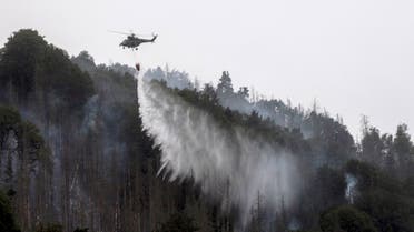 A helicopter drops water in order to contain a wildfire as it continues to burn in a forest near the town of Schmilka, eastern Germany, on July 27, 2022, near the border with the Czech Republic. (AFP)