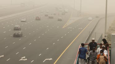 People walk up the stairs toward a bridge during a sand storm in the Gulf emirate of Dubai, on August 14, 2022. (AFP)