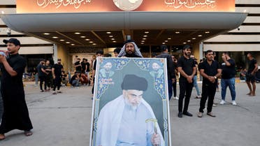A man poses with a picture of Iraqi populist leader Moqtada al-Sadr, during a sit-in at the parliament, amid political crisis in Baghdad, Iraq August 12, 2022. (Reuters)