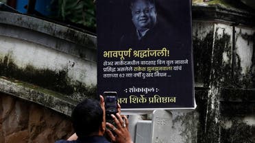 A security guard takes a picture of a poster paying tribute to the late Indian billionaire Rakesh Jhunjhunwala outside his residence after he passed away in Mumbai, India, on August 14, 2022. (Reuters)