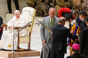 People help a Swiss Guard get back up after he fainted during Pope Francis' (L) weekly general audience on August 17, 2022 at Paul-VI hall in The Vatican. (AFP)