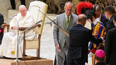 People help a Swiss Guard get back up after he fainted during Pope Francis' (L) weekly general audience on August 17, 2022 at Paul-VI hall in The Vatican. (AFP)