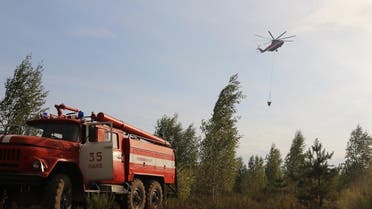 This handout picture released by the Russian Emergency Ministry on August 18, 2022, shows a fire helicopter and a fire engine fighting a wildfire in Ryazan region outside Moscow. (AFP)