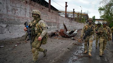 FILE - Russian soldiers patrol a destroyed part of the Illich Iron & Steel Works Metallurgical Plant in Mariupol, in territory under the government of the Donetsk People's Republic, eastern Ukraine, Wednesday, May 18, 2022. Despite getting bogged down in Ukraine, the Kremlin has resisted announcing a full-blown mobilization, a move that could prove to be very unpopular for President Vladimir Putin. That has led instead to a covert recruitment effort that includes trying to get prisoners to make up for the manpower shortage. This photo was taken during a trip organized by the Russian Ministry of Defense. (AP Photo, File)