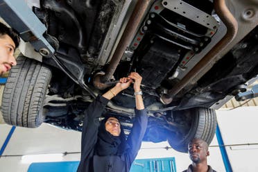 Huda al-Matrooshi, an Emirati woman who owns and runs a car repair garage, fixes a car with her team at her garage in Sharjah, United Arab Emirates April 21, 2021. (Reuters)