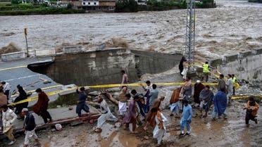 People gather in front of a road damaged by flood waters following heavy monsoon rains in Madian area in Pakistan's northern Swat Valley on August 27, 2022. (AFP)