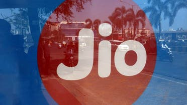 Commuters are reflected on an advertisement of Reliance Industries’ Jio telecoms unit, at a bus stop in Mumbai, India. (Reuters)