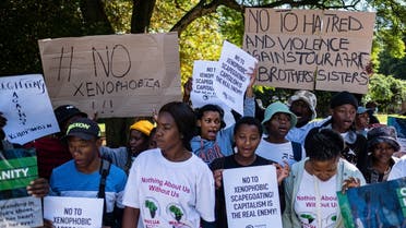 South Africans and foreign migrants hold banner and shout slogan during a demonstration against xenophobia in Johannesburg, on March 26, 2022 organized by the activist movement against xenophobic attacks Kopanang Africa. (AFP)