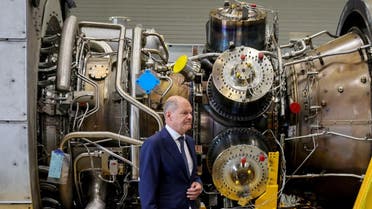German Chancellor OIaf Scholz stands next to a gas turbine meant to be transported to the compressor station of the Nord Stream 1 gas pipeline in Russia during his visit to Siemens Energy's site in Muelheim an der Ruhr, Germany, on August 3, 2022. (Reuters)