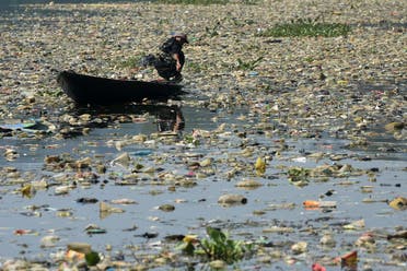 A scavenger paddles his wooden boat to collect plastic waste for recycling on the Citarum river choked with garbage and industrial waste, in Bandung, West Java province on June 26, 2019. (AFP)