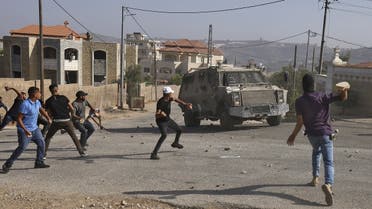 Palestinian youths throw rocks at an Israeli army jeep in the town of Silwad, near the city of Ramallah in the occupied West Bank, after a military operation in the town, on August 31, 2022. (AFP)