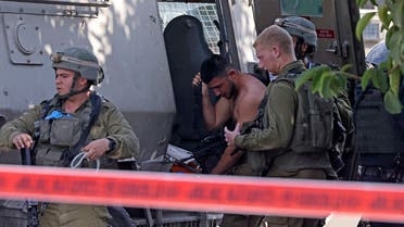 Israeli soldiers gather around an injured soldier at the scene of a reported stabbing attack in Hebron in the Israeli occupied West Bank, on September 2, 2022. (AFP)  