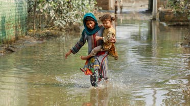 A girl carries her sibling as she walks through stranded flood water, following rains and floods during the monsoon season in Nowshera, Pakistan September 4, 2022. REUTERS/Fayaz Aziz TPX IMAGES OF THE DAY