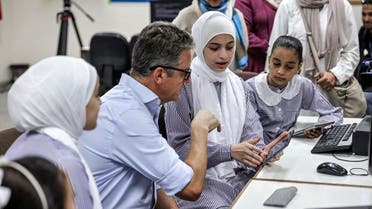 Thomas White, director of United Nations Relief and Works Agency for Palestine Refugees (UNRWA), instructs students at an UNRWA school on how to use one of the new electronic tablets in class, in Gaza City on September 7, 2022. (AFP)