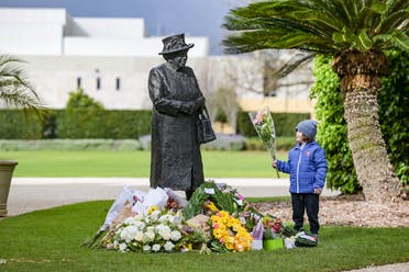 A boy places flowers at the base of a statue of Queen Elizabeth II at Government House in Adelaide after her passing away on September 9, 2022. (AFP)