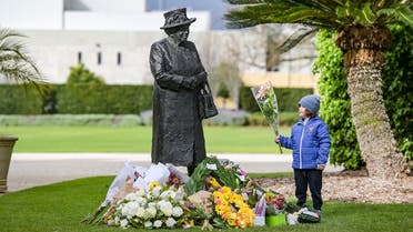 A boy places flowers at the base of a statue of Queen Elizabeth II at Government House in Adelaide after her passing away on September 9, 2022. (AFP)