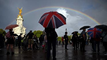 A person with an Union flag-themed umbrella shelters from the rain by the Queen Victoria Memorial opposite Buckingham Palace, central London, on September 8, 2022. (AFP)
