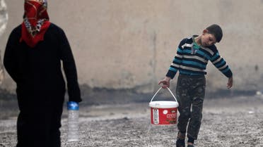 An internally displaced boy carries a bucket filled with water at an empty school and university compound used as shelter, in Azaz, Syria February 21, 2020. REUTERS/Khalil Ashawi