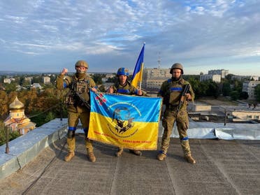 Soldados ucranianos sostienen una bandera en una azotea en Kupiansk, Ucrania, en esta imagen obtenida de las redes sociales publicada el 10 de septiembre de 2022. (Reuters)