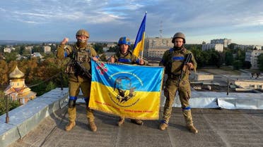 Ukrainian soldiers hold a flag at a rooftop in Kupiansk, Ukraine in this picture obtained from social media released on September 10, 2022. (Reuters)