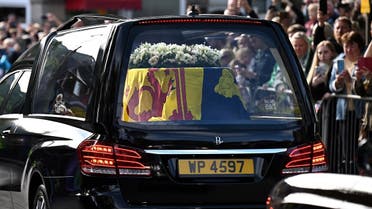 Members of the public pay their respects as they hearse carrying the coffin of Queen Elizabeth II, draped in the Royal Standard of Scotland, is driven through Ballater, September 11, 2022. (AFP)