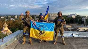 Ukrainian soldiers hold a flag at a rooftop in Kupiansk, Ukraine in this picture obtained from social media released on September 10, 2022. Telegram @kuptg/via REUTERS