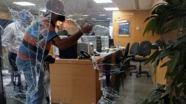 Men are seen through a shattered window of a BLOM Bank branch, where a security source said a group of depositors, at least one of whom is armed, took hostages in Beirut, Lebanon, on September 14, 2022. (Reuters)