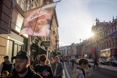 Pedestrians walk past a banner with a portrait of Britain's Queen Elizabeth, following her death, in London, Britain, September 17, 2022. (Reuters)