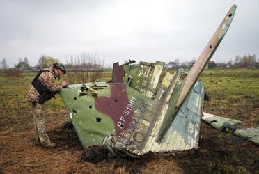 فحص جندي أوكراني شظية من طائرة تابعة للقوات الجوية الروسية بعد معركة في وقت سابق من هذا العام في قرية كولونشينا. (أ ب)